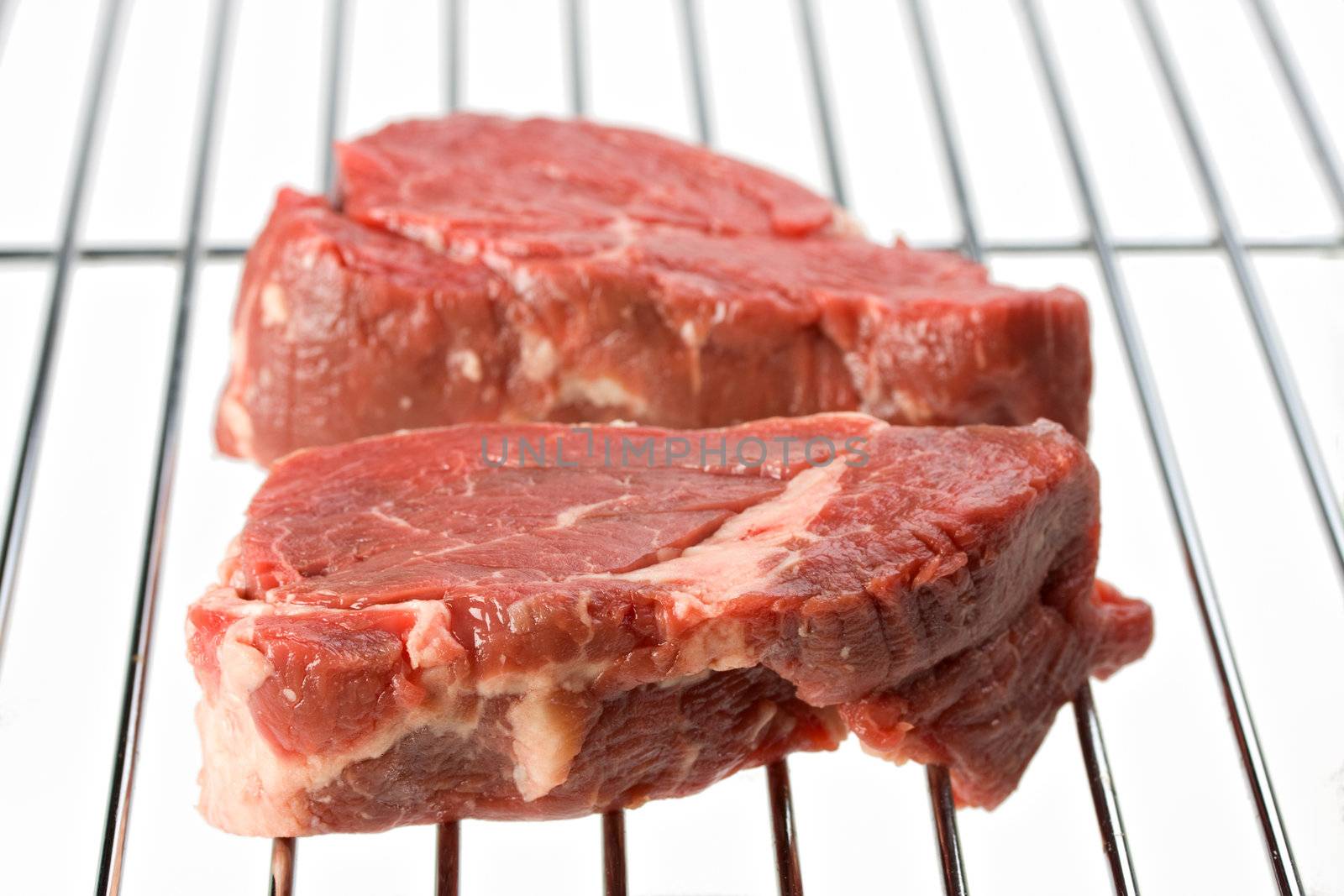 raw steak on a grill isolated on white by bernjuer