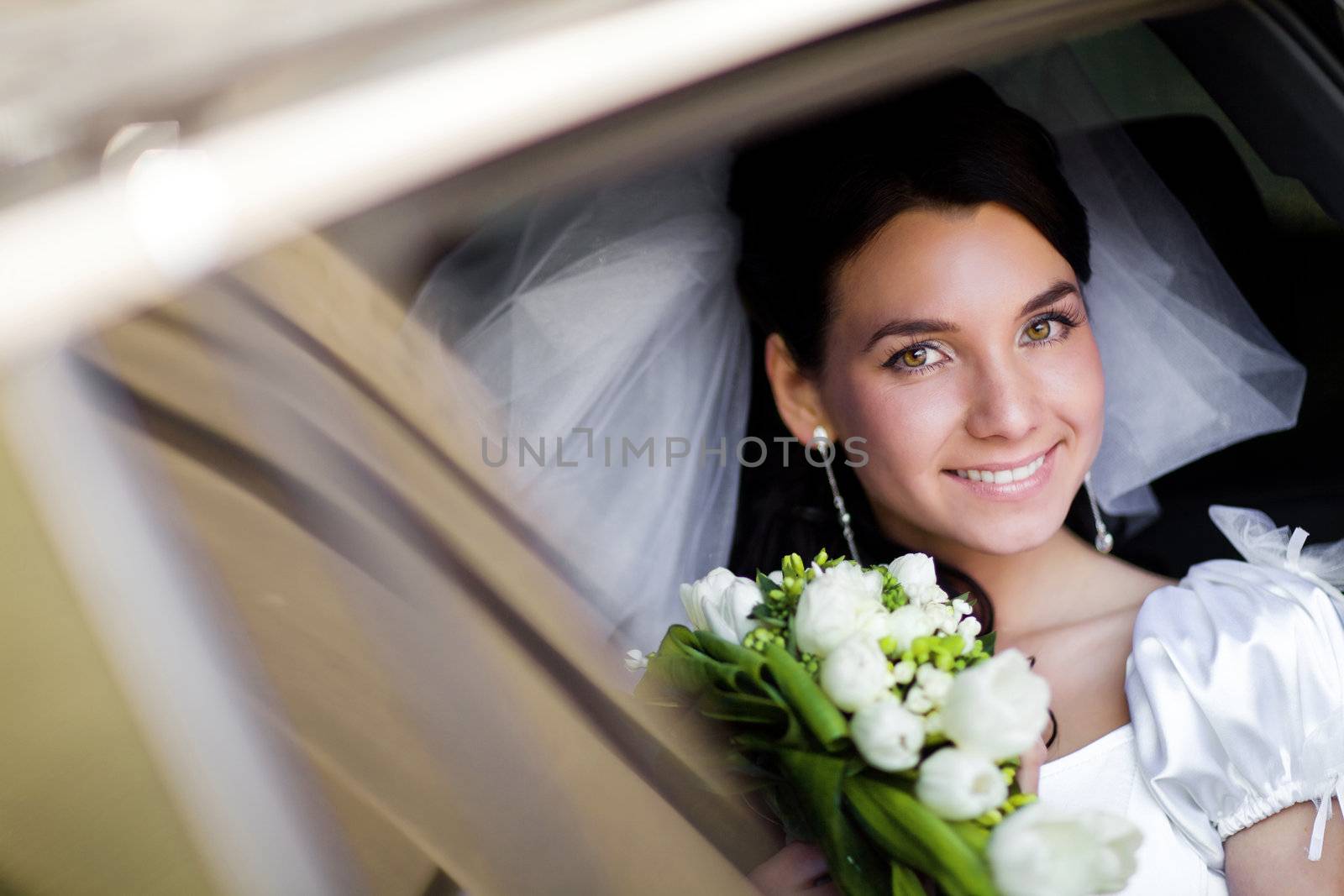 happy bride with flower bouquet siting in the car