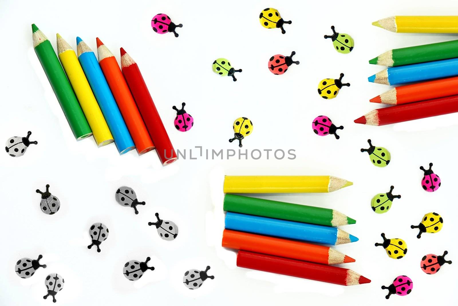 various small crayons and ladybirds isolated over white