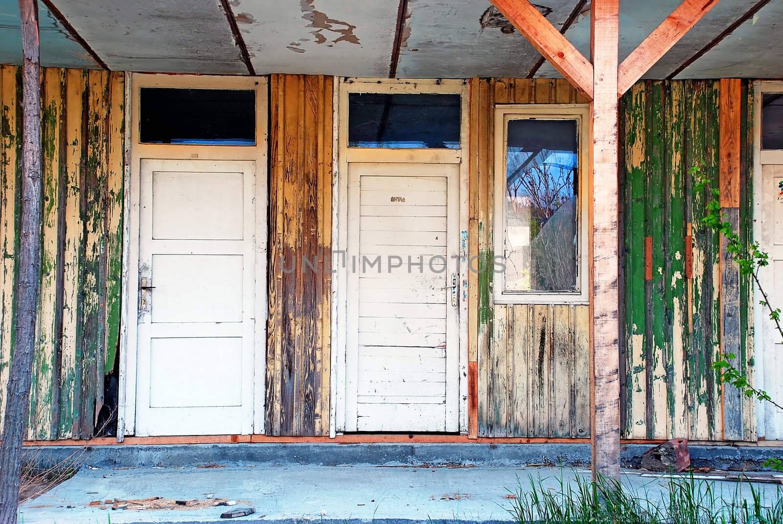 two old wooden white doors broken window of abandoned ruined house