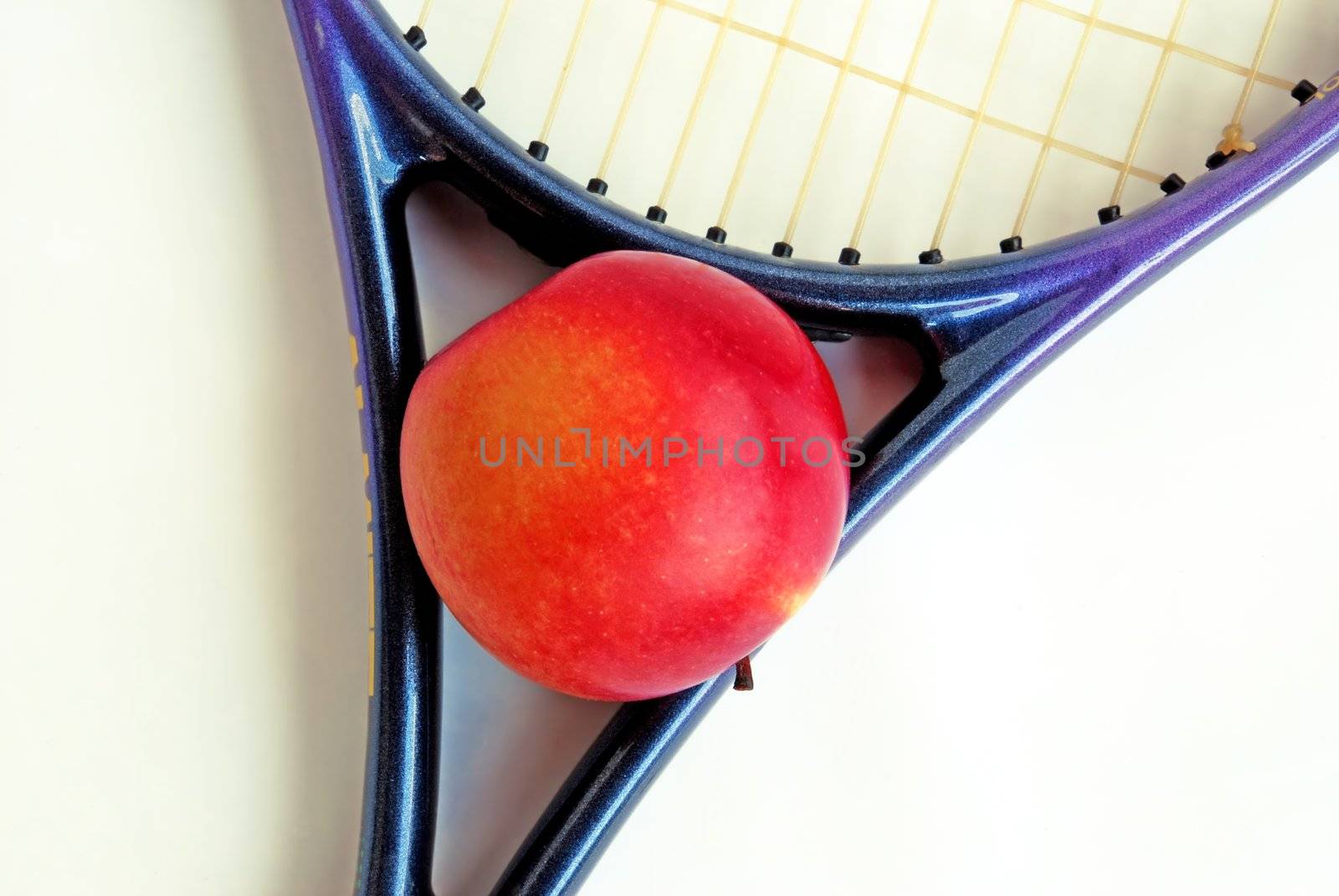 red apple in tennis racket over white isolated