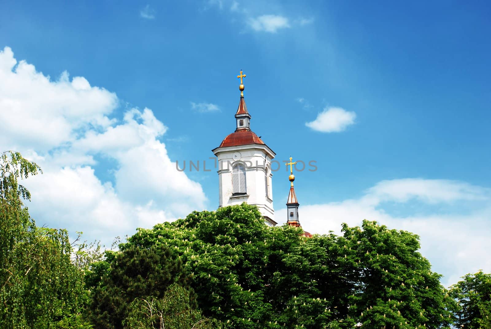 white tower of church with gold cross over blue