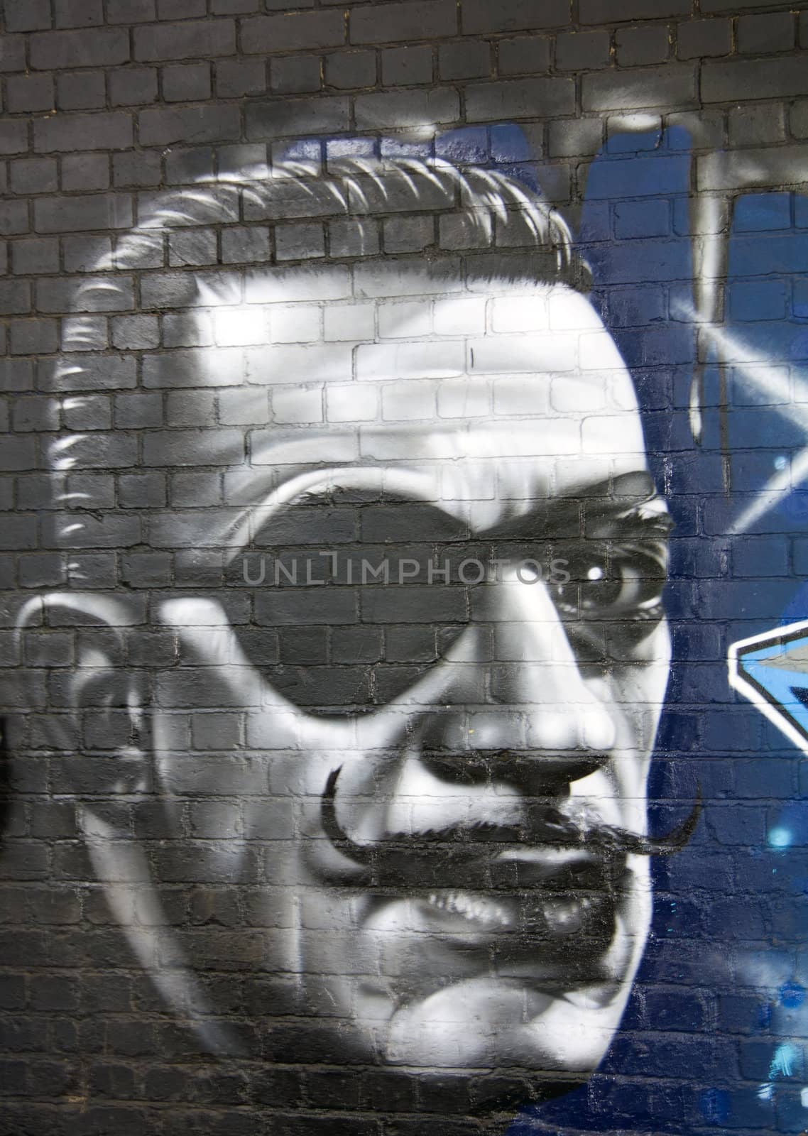 Graffiti on a wall depicting a man's face with a patch on his eye