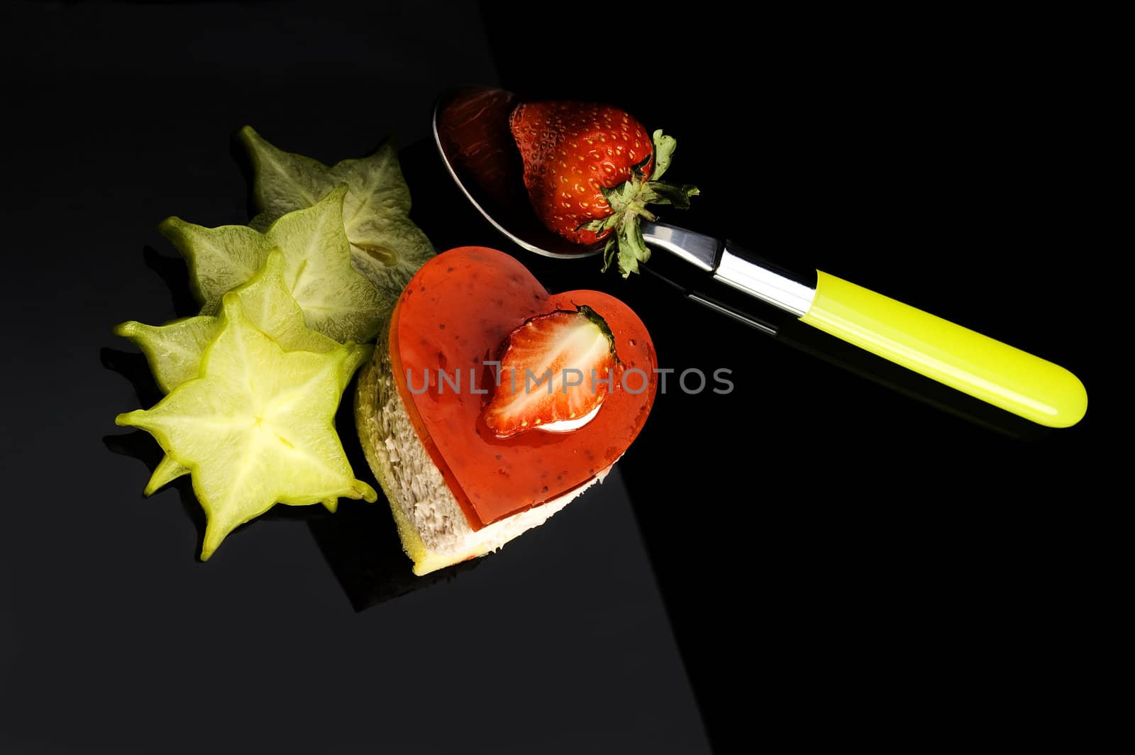 heart shaped strawberry cake with carambola or star fruit decoration over black background