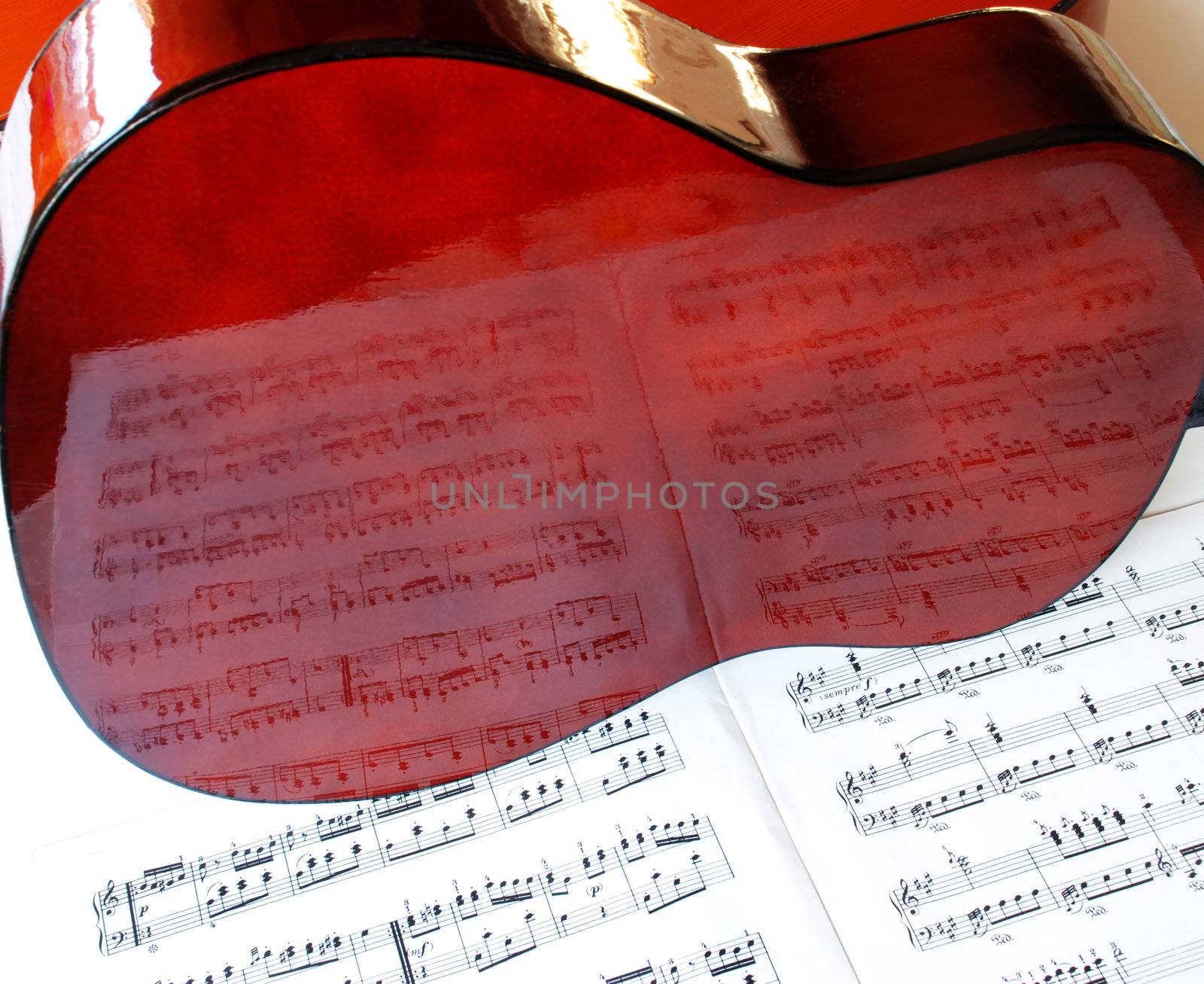 Shining acoustical guitar over music book with notes