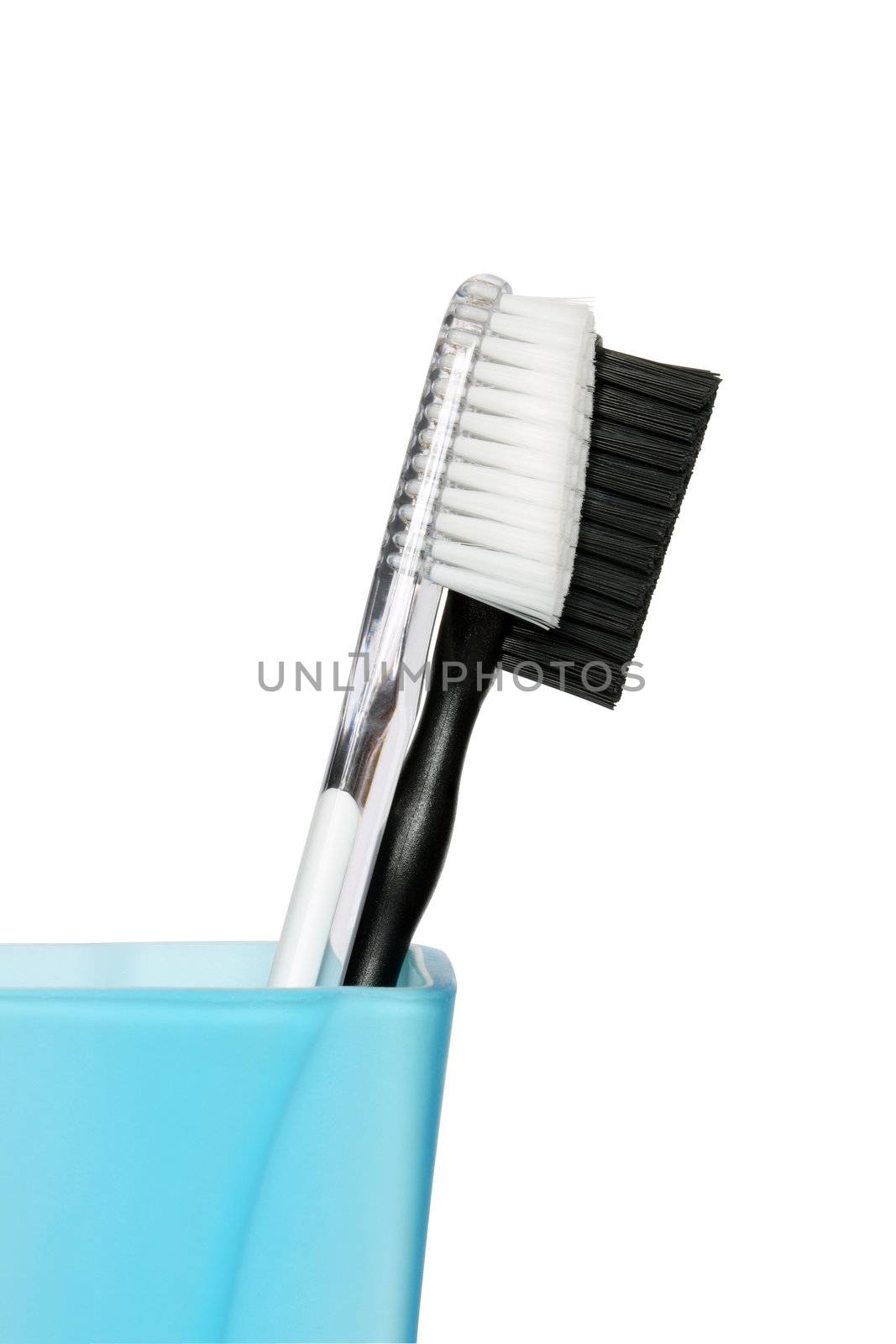 Black and white toothbrushes in blue glass. Isolated with clipping path