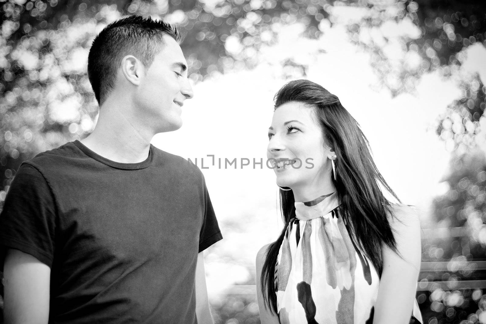 A happy young couple in their mid 20s smiling in black and white.