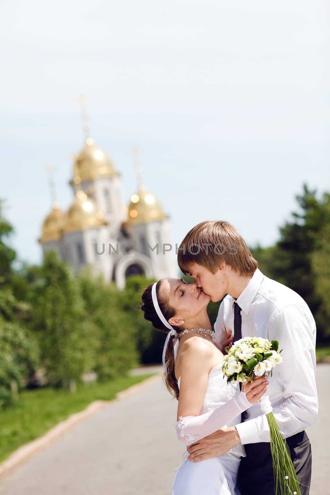 bride and groom kissing in the park