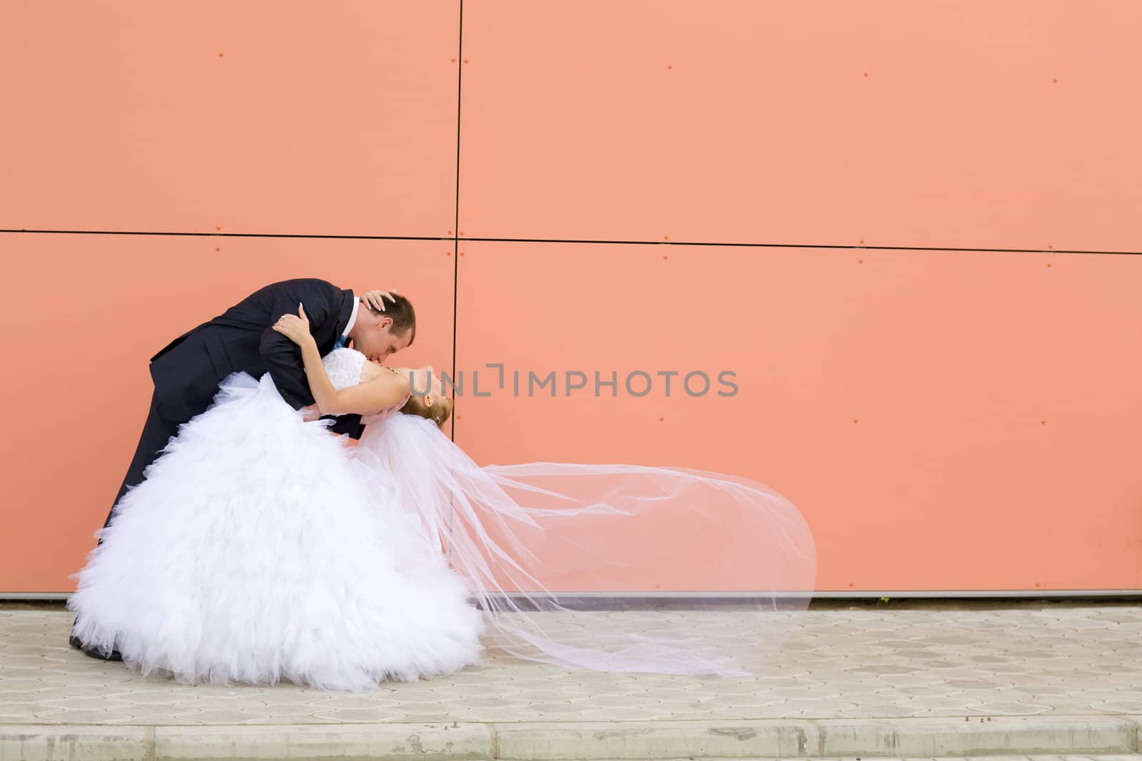 kiss of bride and groom near the wall 