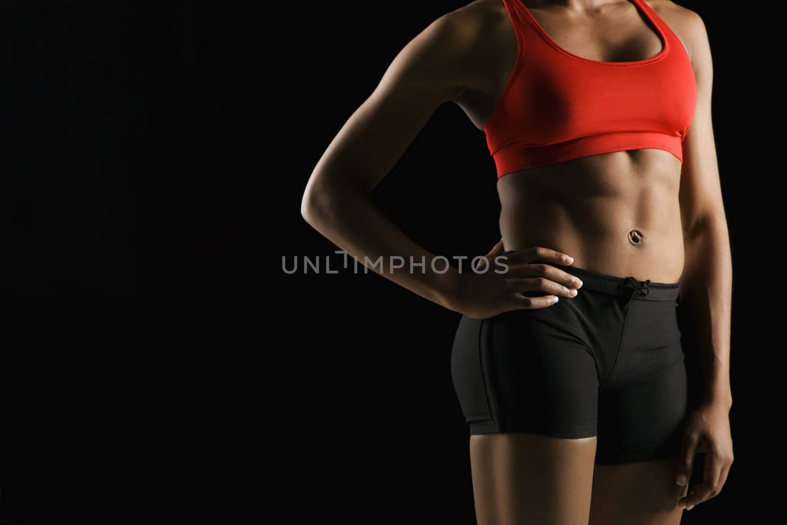 Torso of muscular African American woman wearing athletic apparel with hand on hip.
