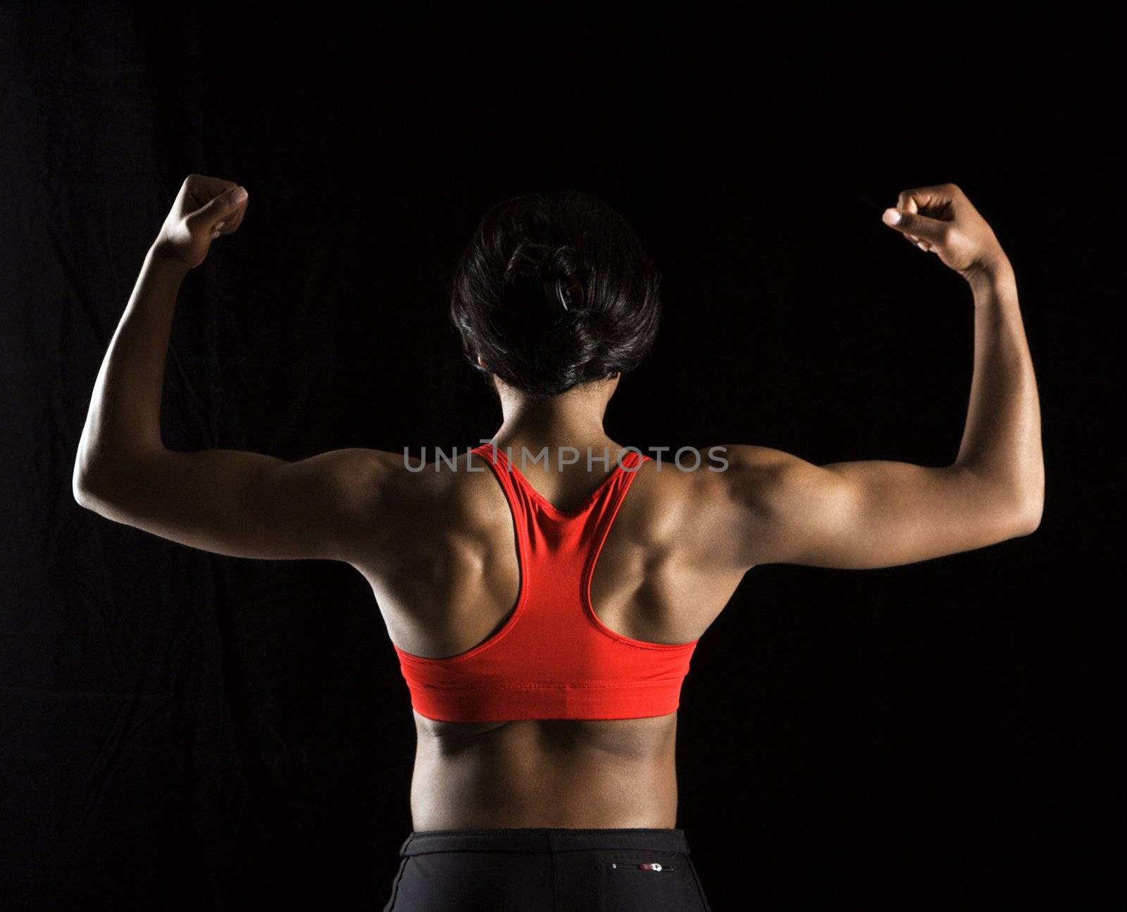 Back of muscular African American woman with biceps flexed.