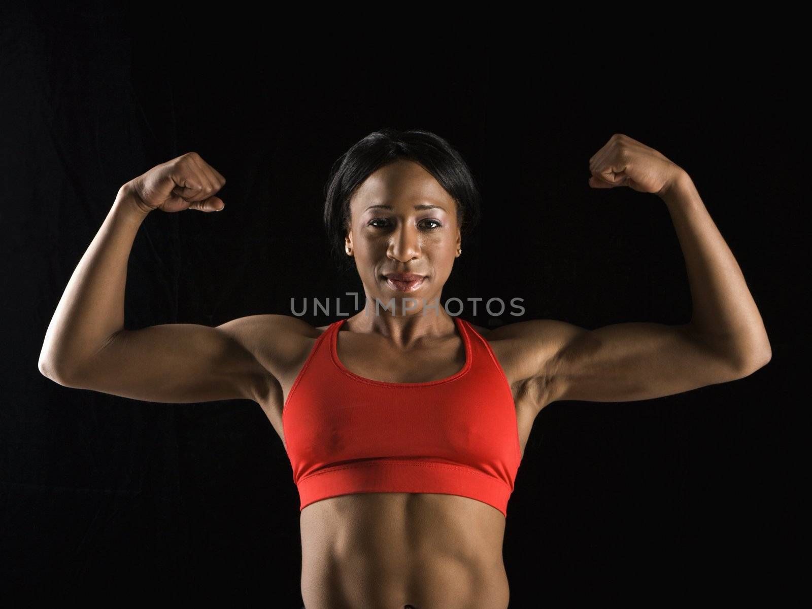 Muscular African American woman looking at viewer with biceps flexed.