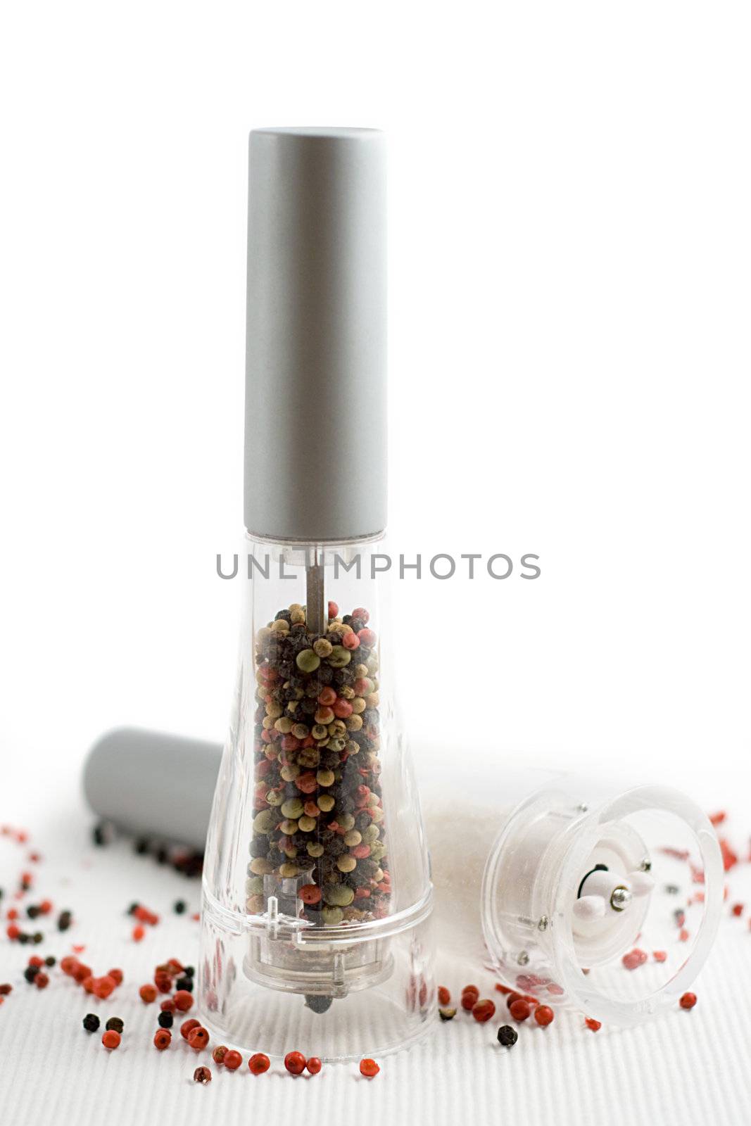 salt and pepper grinders on a table, with pepper spread around