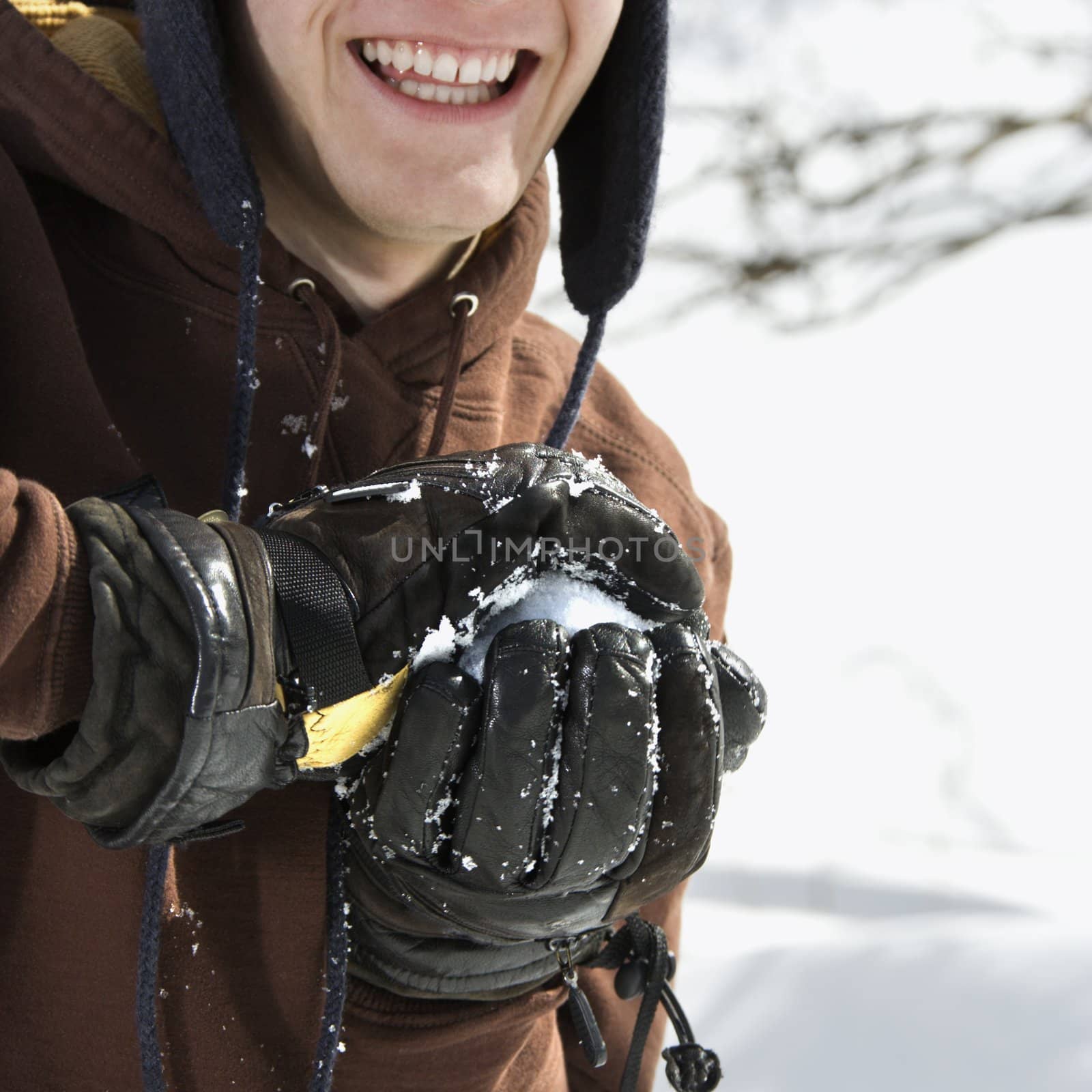 Caucasian male teenager making snowball in winter setting.