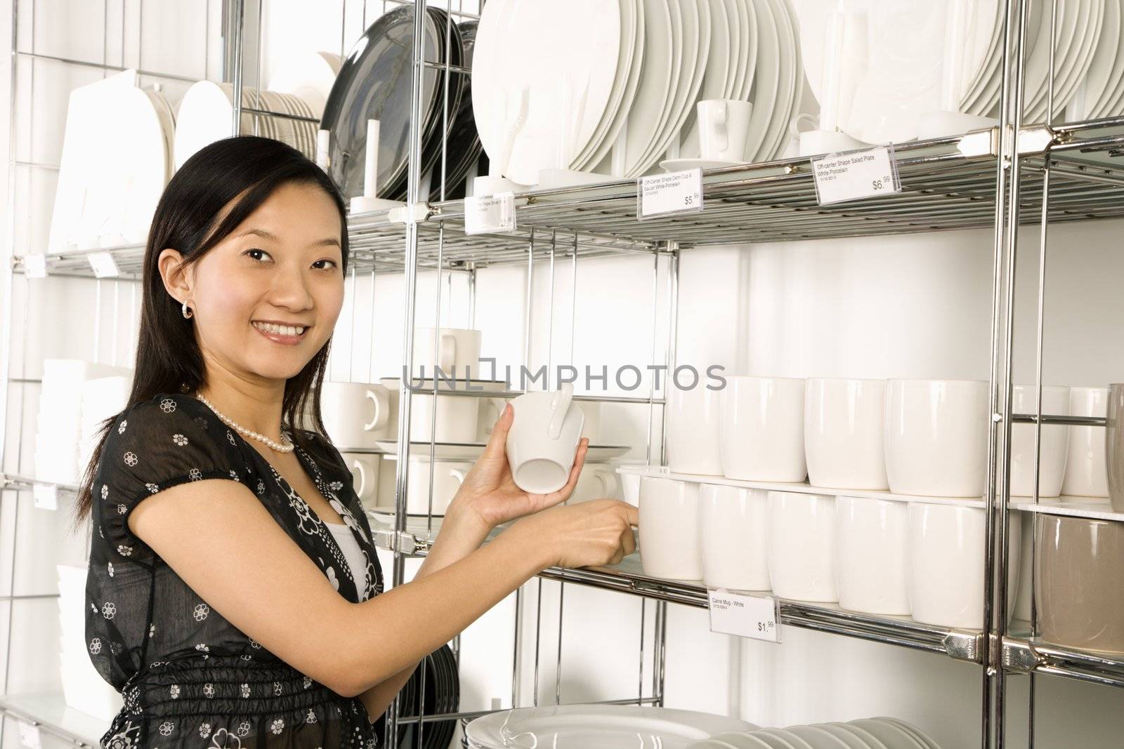 Asian female shopping for dishes and glasses in retail store.