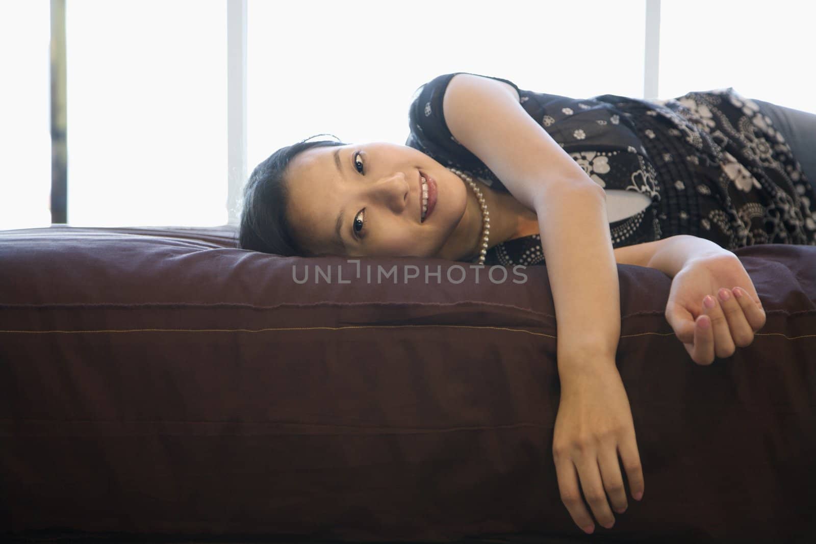 Portrait of Asian female lying on bed looking at viewer.