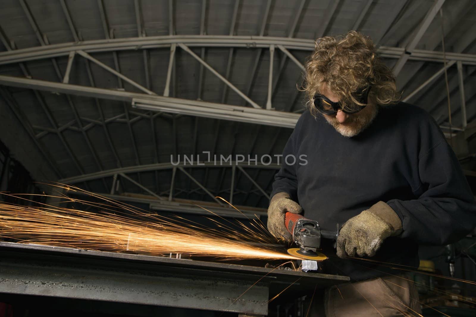 Caucasian male metalsmith shaping metal and creating sparks.
