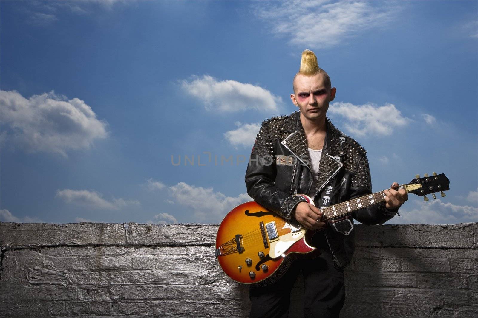 Portrait of mid-adult Caucasian male punk holding guitar.