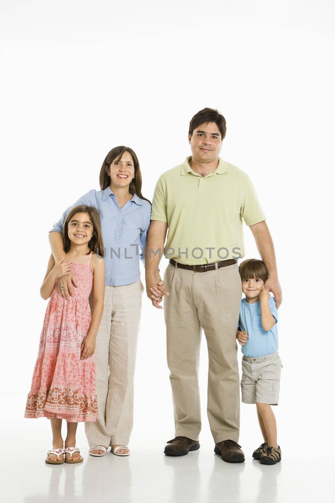 Hispanic family of four standing against white background.