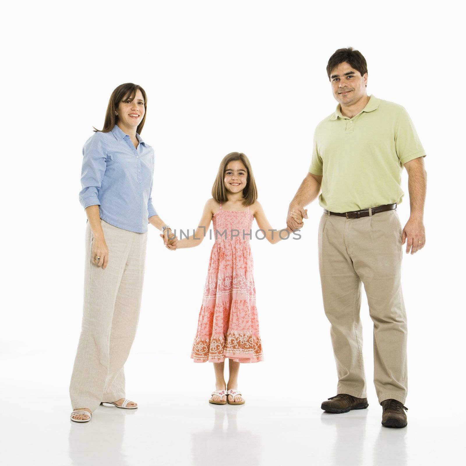 Hispanic parents and daughter holding hands standing against white background.