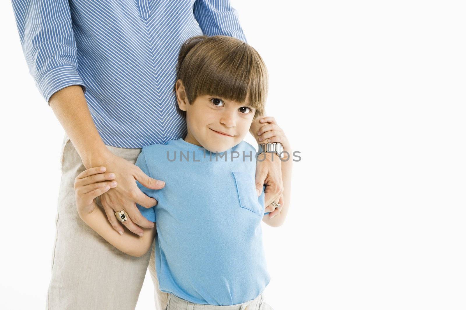 Boy standing with mother against white background.