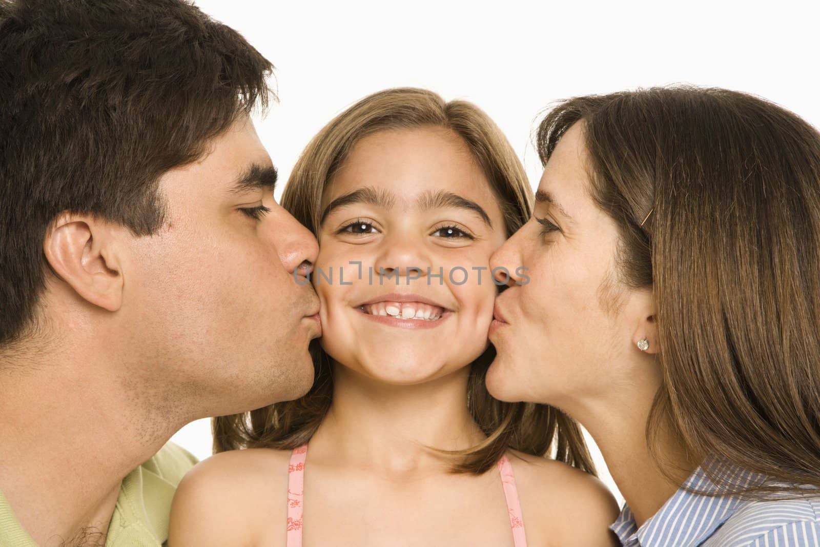 Mother and father kissing smiling daughter on opposite cheeks.