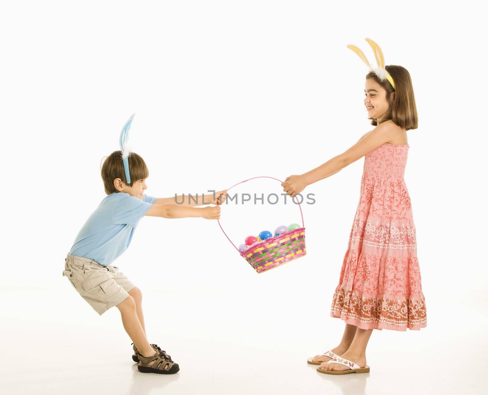 Boy and girl wearing bunny ears fighting over Easter basket.