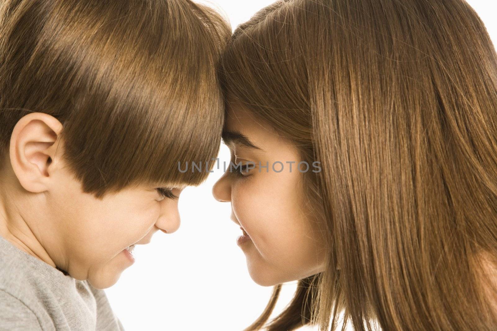 Boy and girl with heads together making mean faces.