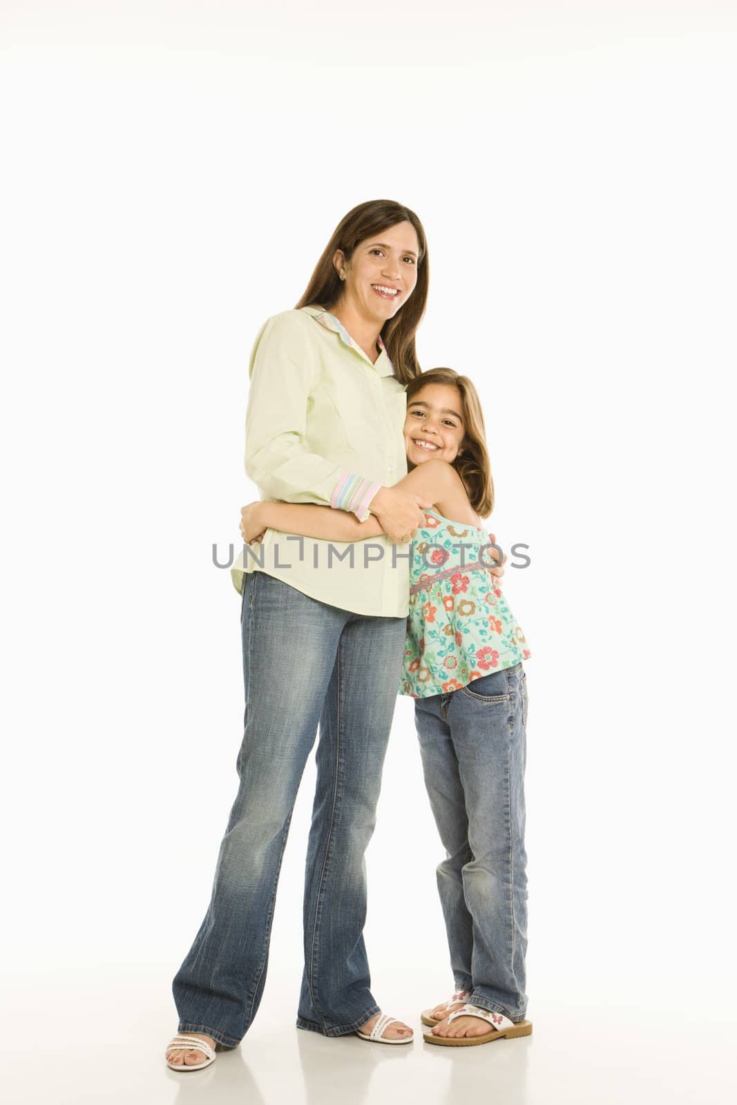 Full length portrait of mother and daughter standing hugging.