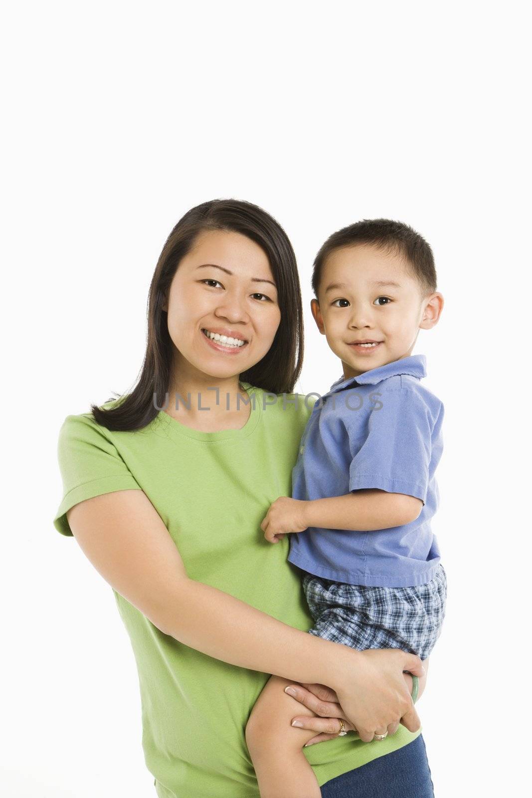 Asian mother holding son on hip smiling in front of white background.