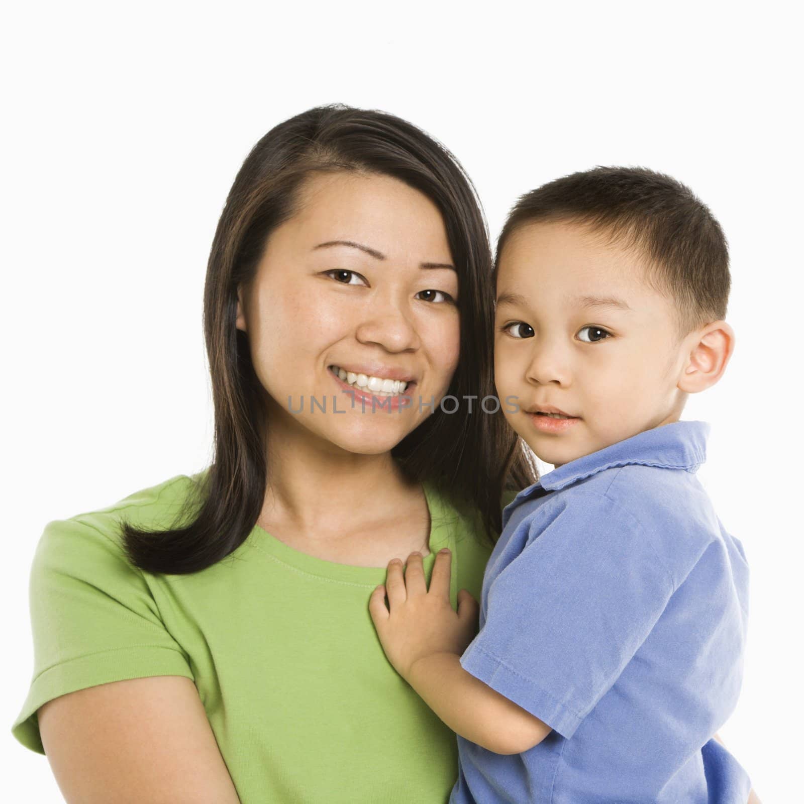 Asian mother holding son smiling in front of white background.