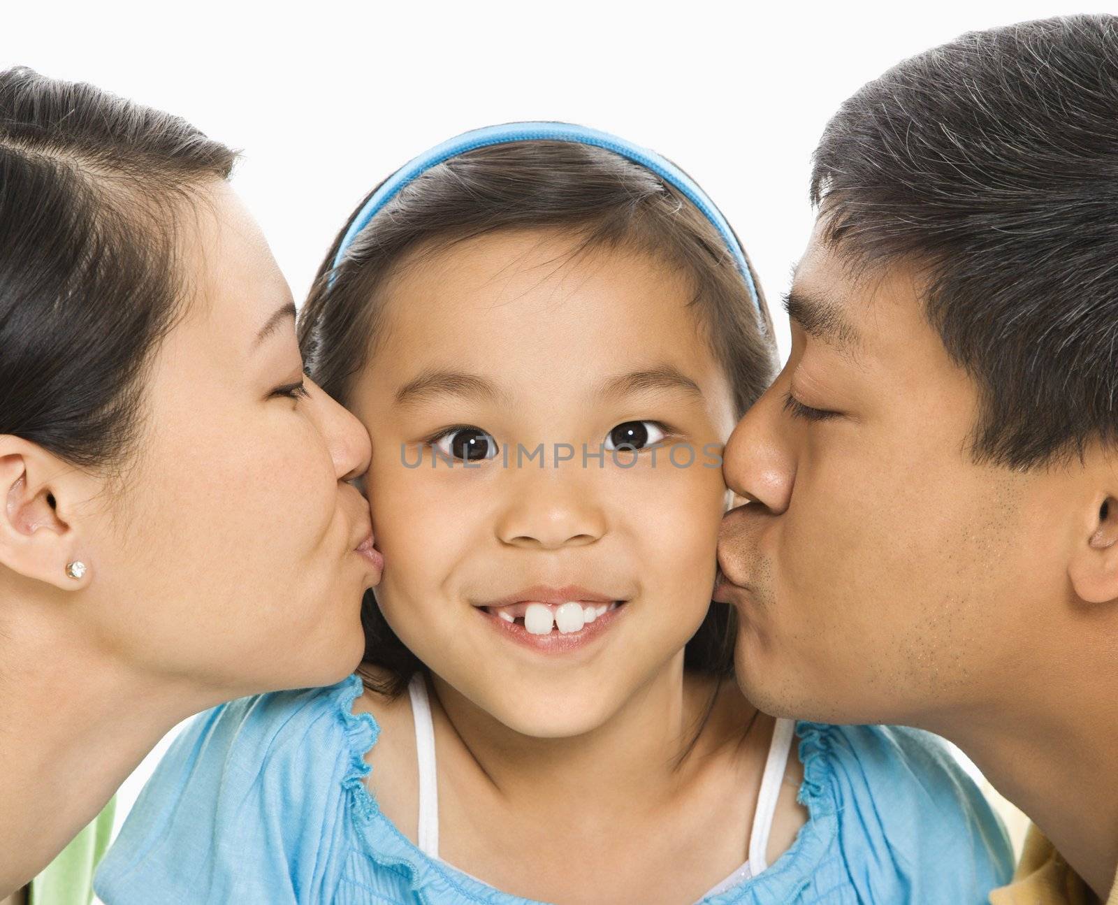 Parents kissing girl. by iofoto