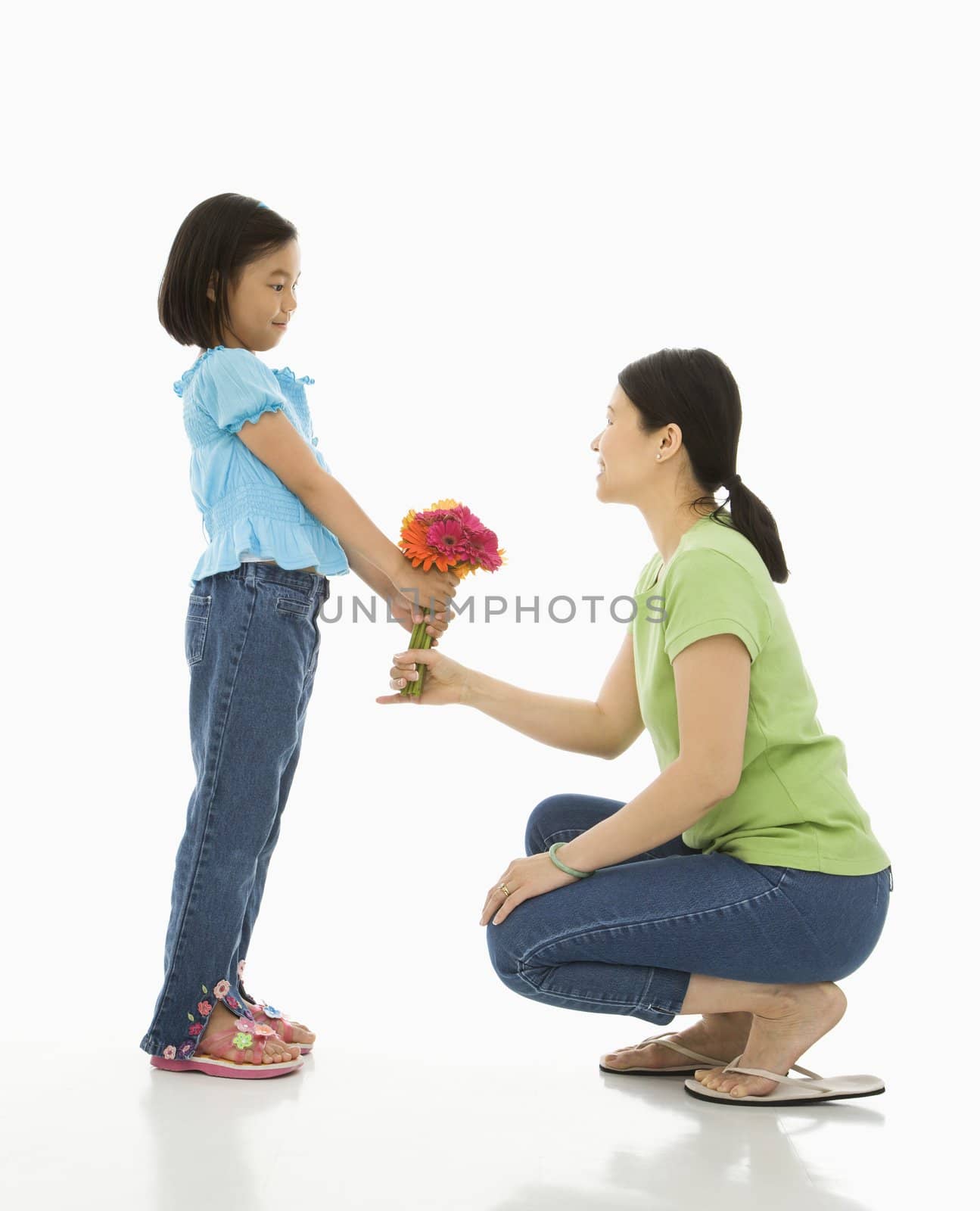 Asian girl handing bouquet of flowers to her mother.