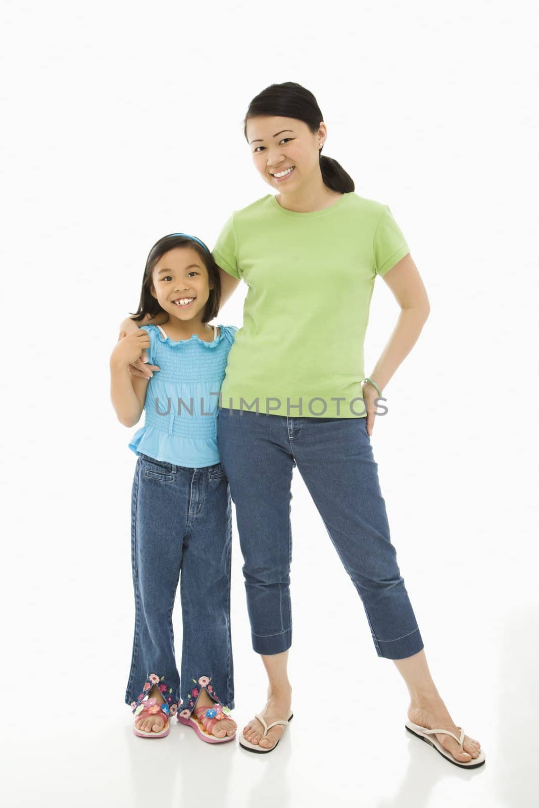 Asian mother and daughter standing with arms around eachother.