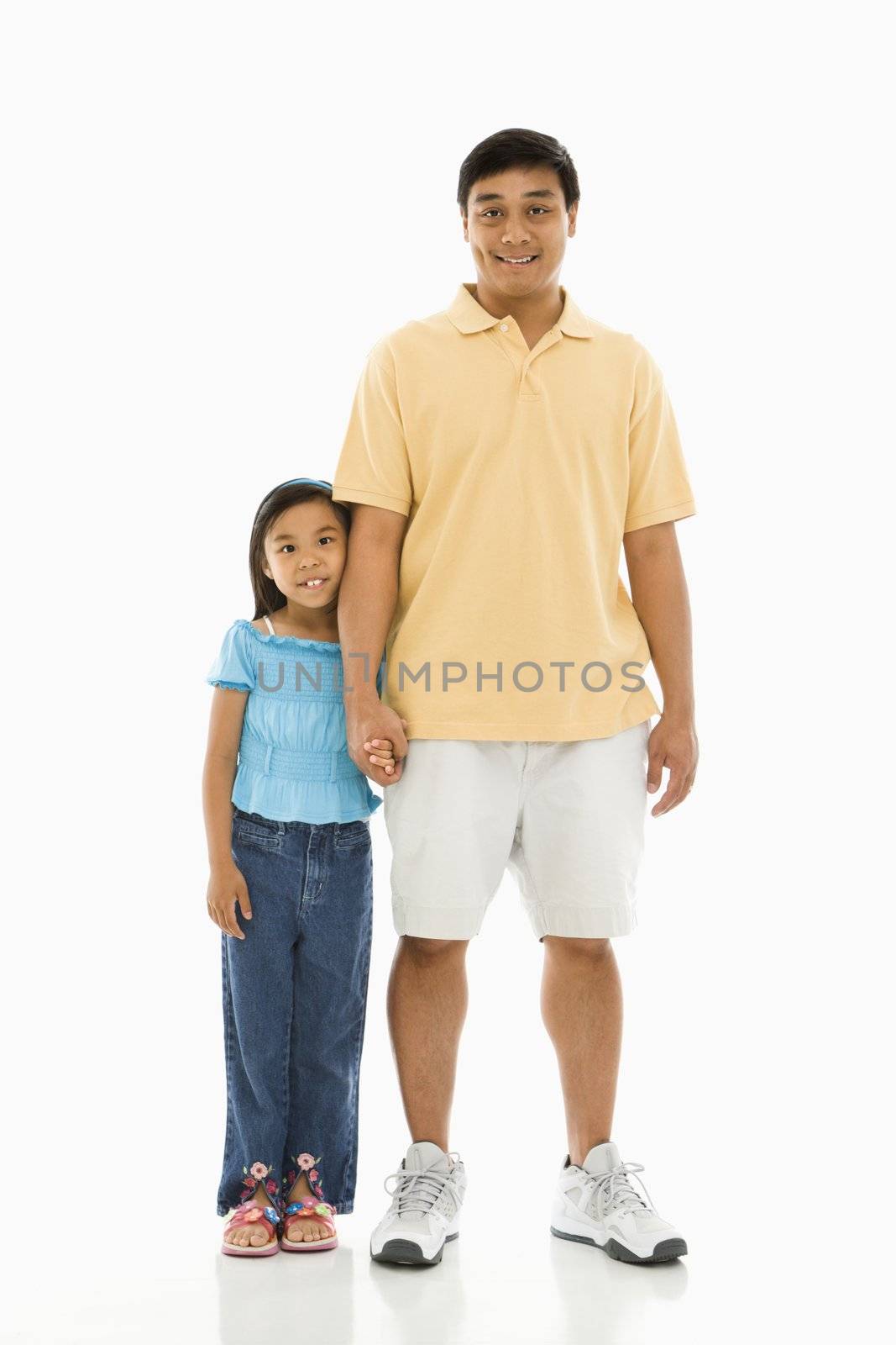 Asian father standing holding hands with daughter.
