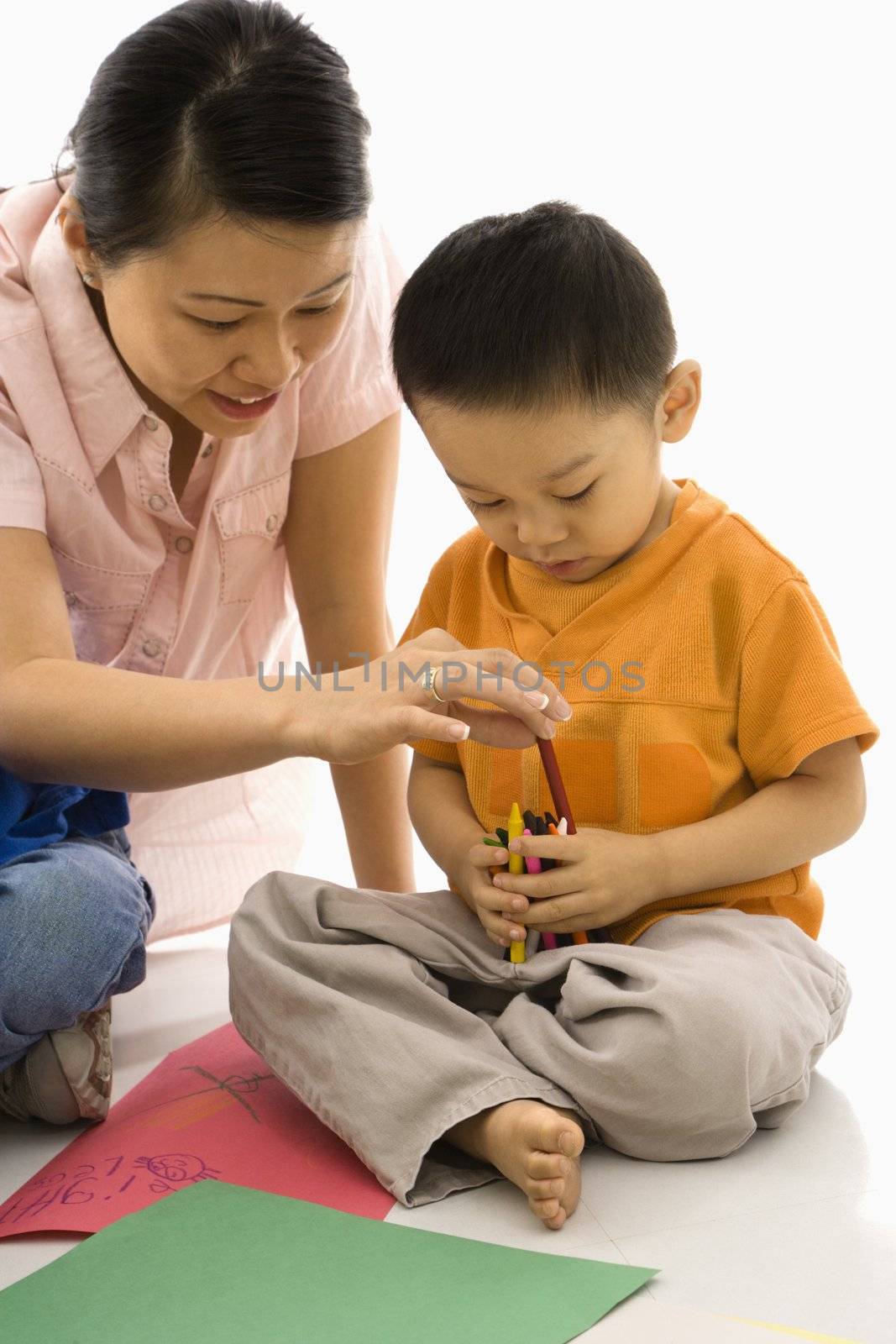 Asian boy and mother coloring with crayons.