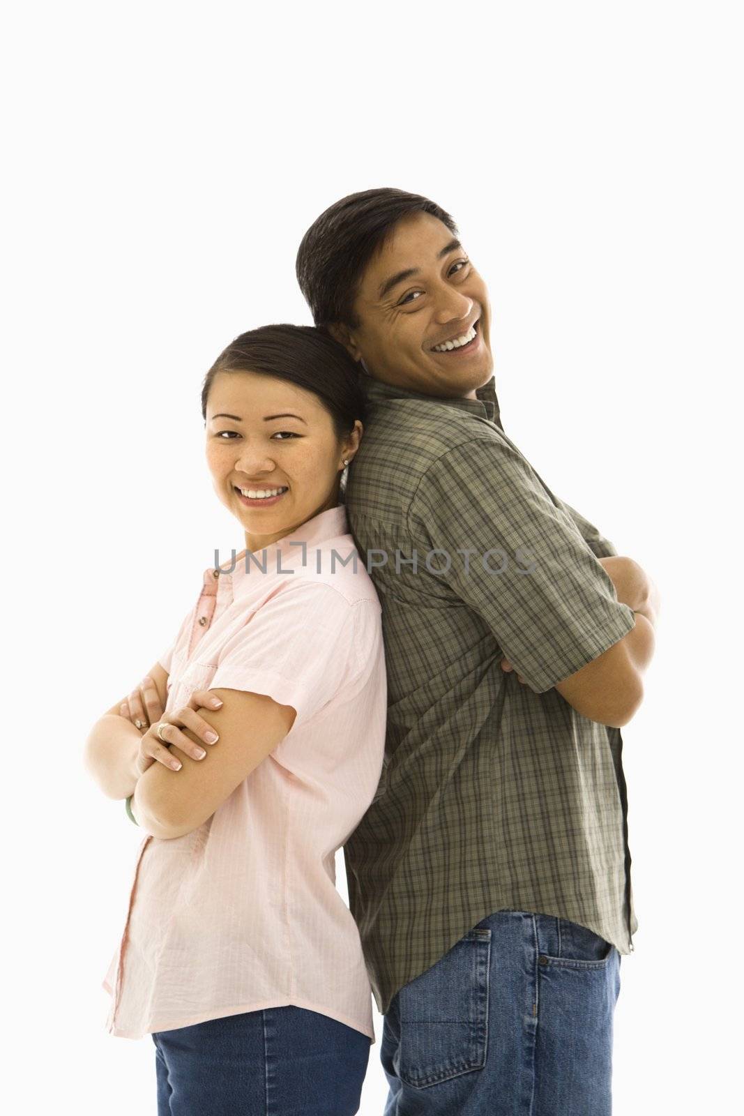 Asian man and woman standing back to back and smiling.