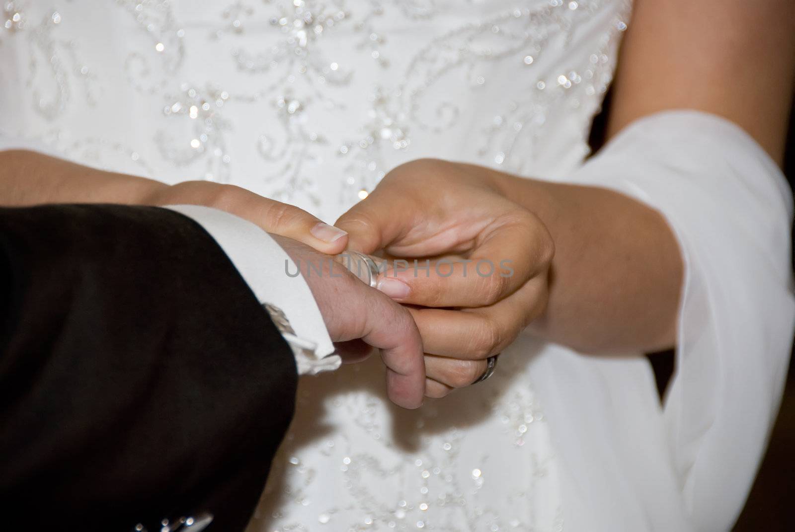 the bride attaching the ring to the grooms finger at a wedding ceremony