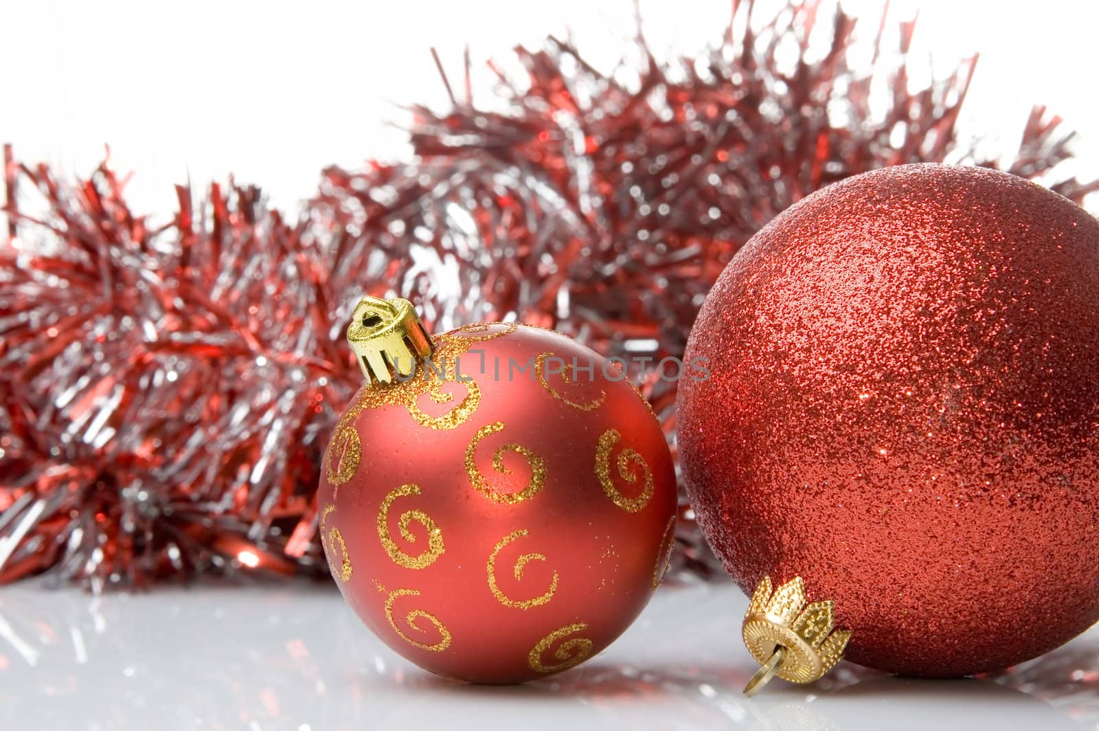 Two red christmas balls with shiny red tinsel