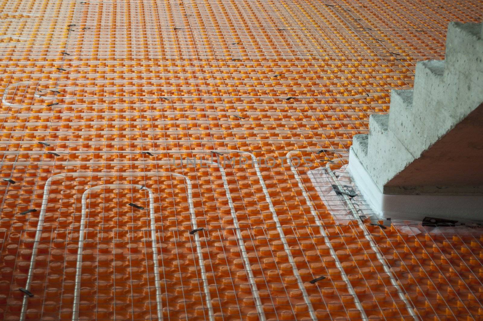 Orange Underfloor heating tube in a construction site with stairs