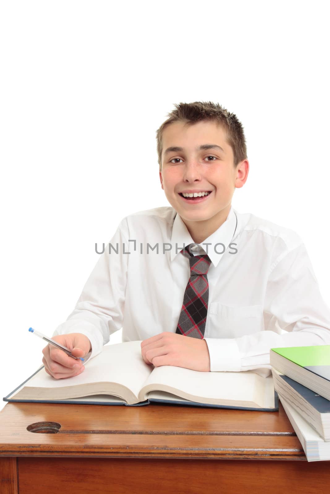 A happy high school student sitting at desk with books.