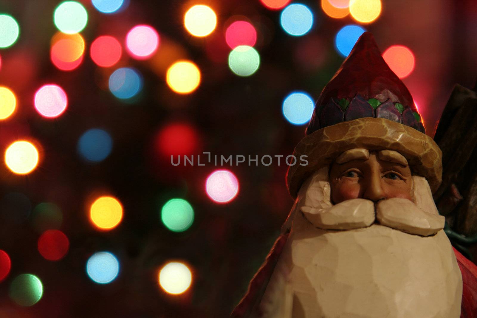 A santa claus figurine with Christmas lights in the background.