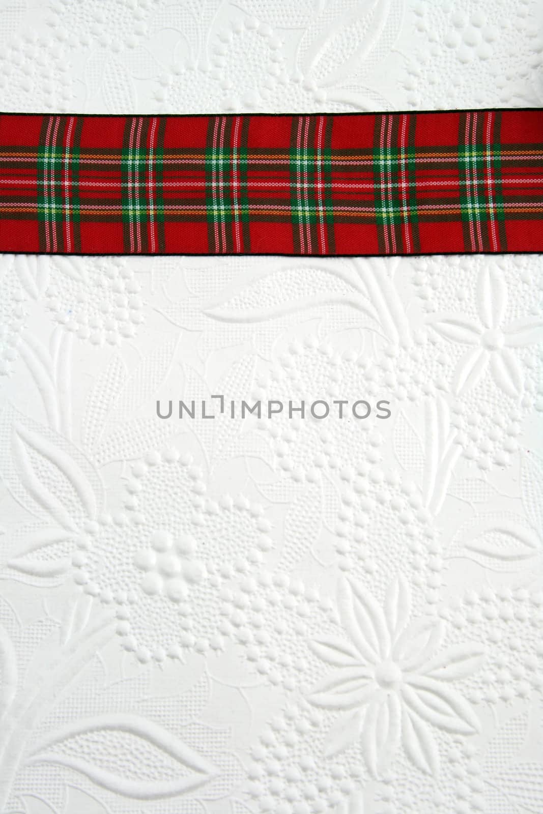 A plaid christmas ribbon on decorative white paper.
