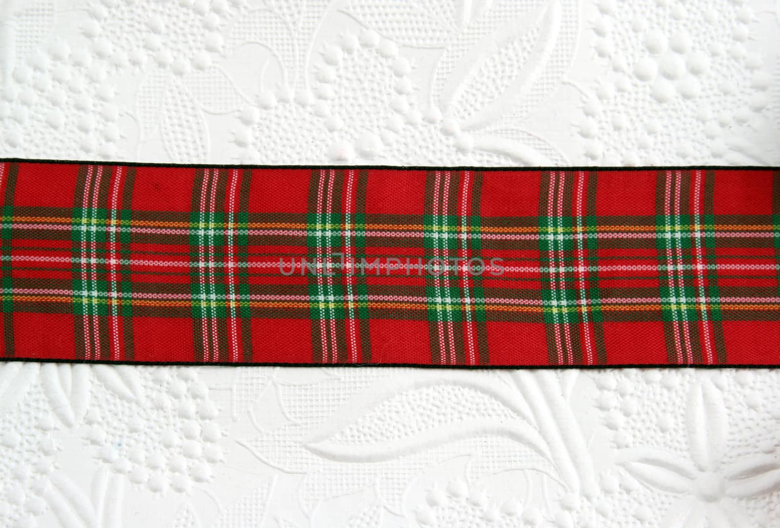 A plaid christmas ribbon on decorative white paper.
