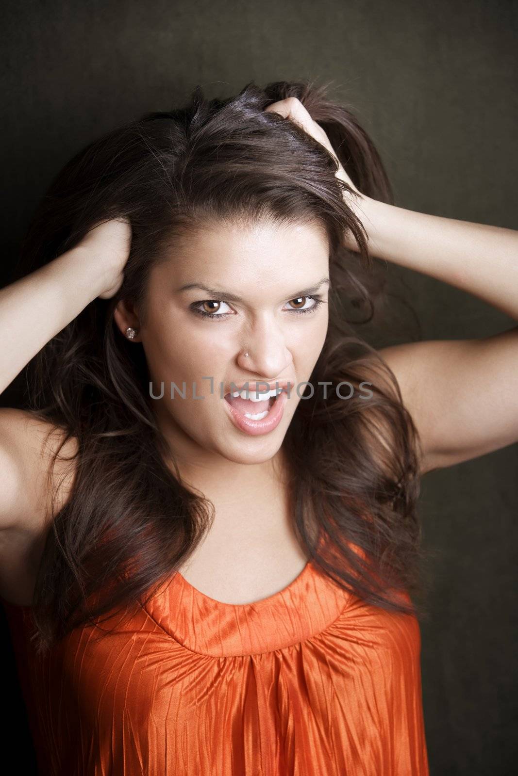 Frustrated Hispanic woman in orange on green background