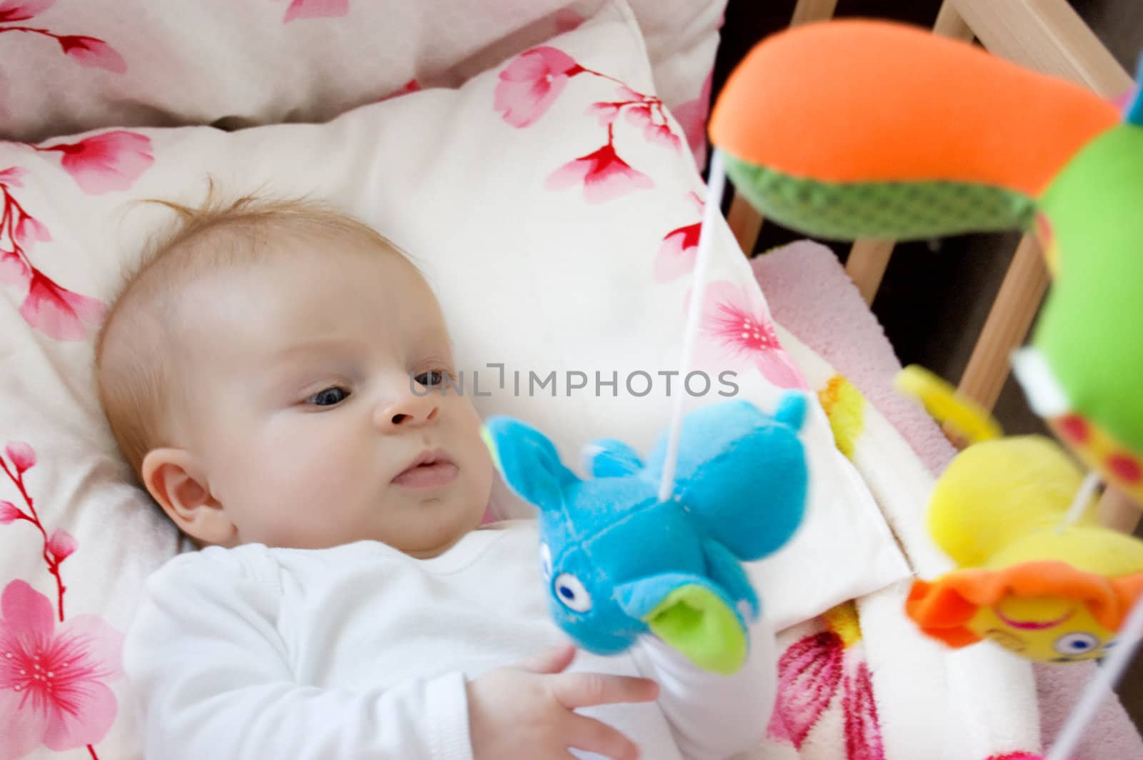 Four months old baby girl playing with toys