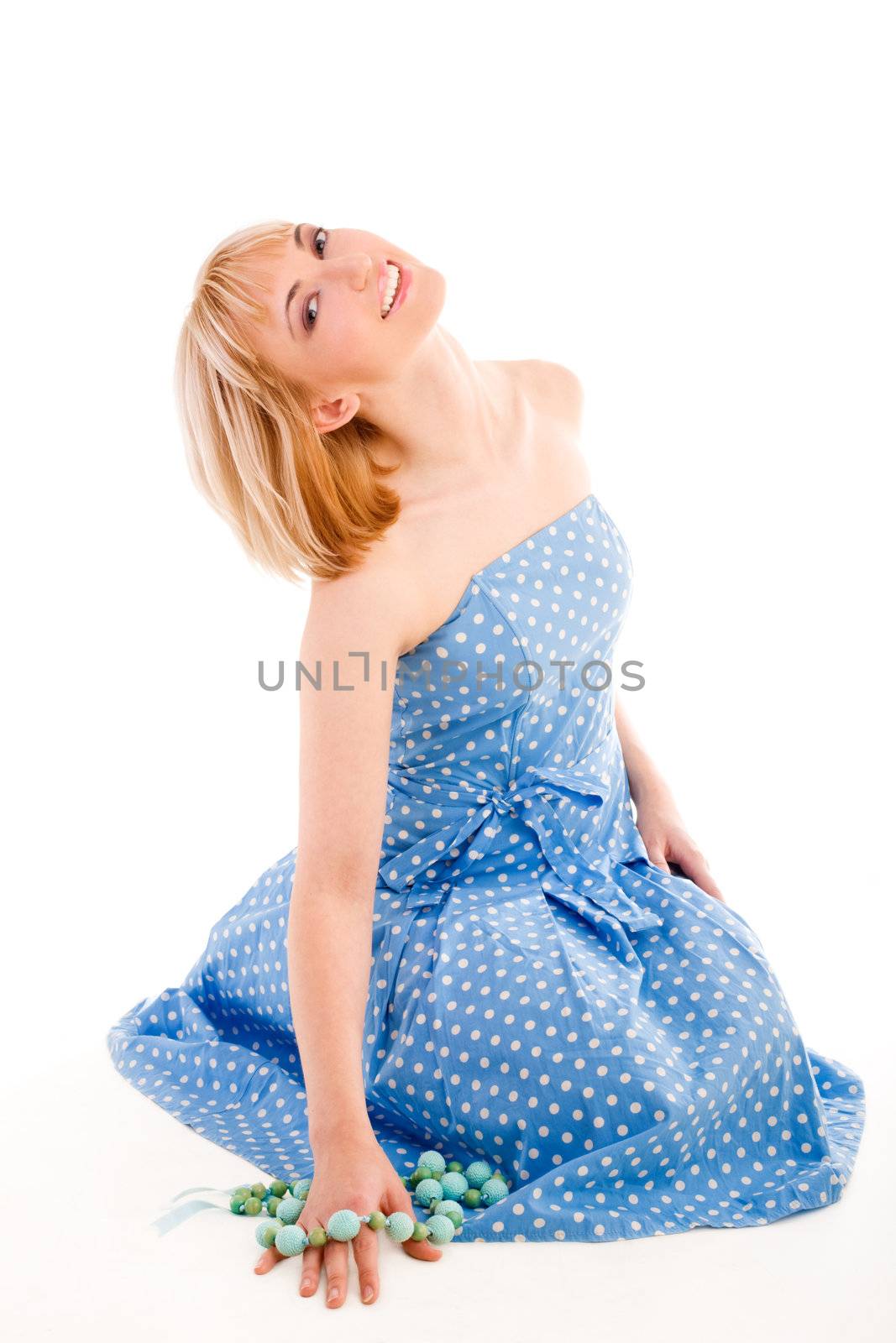 Sitting girl in a blue dress holding beads