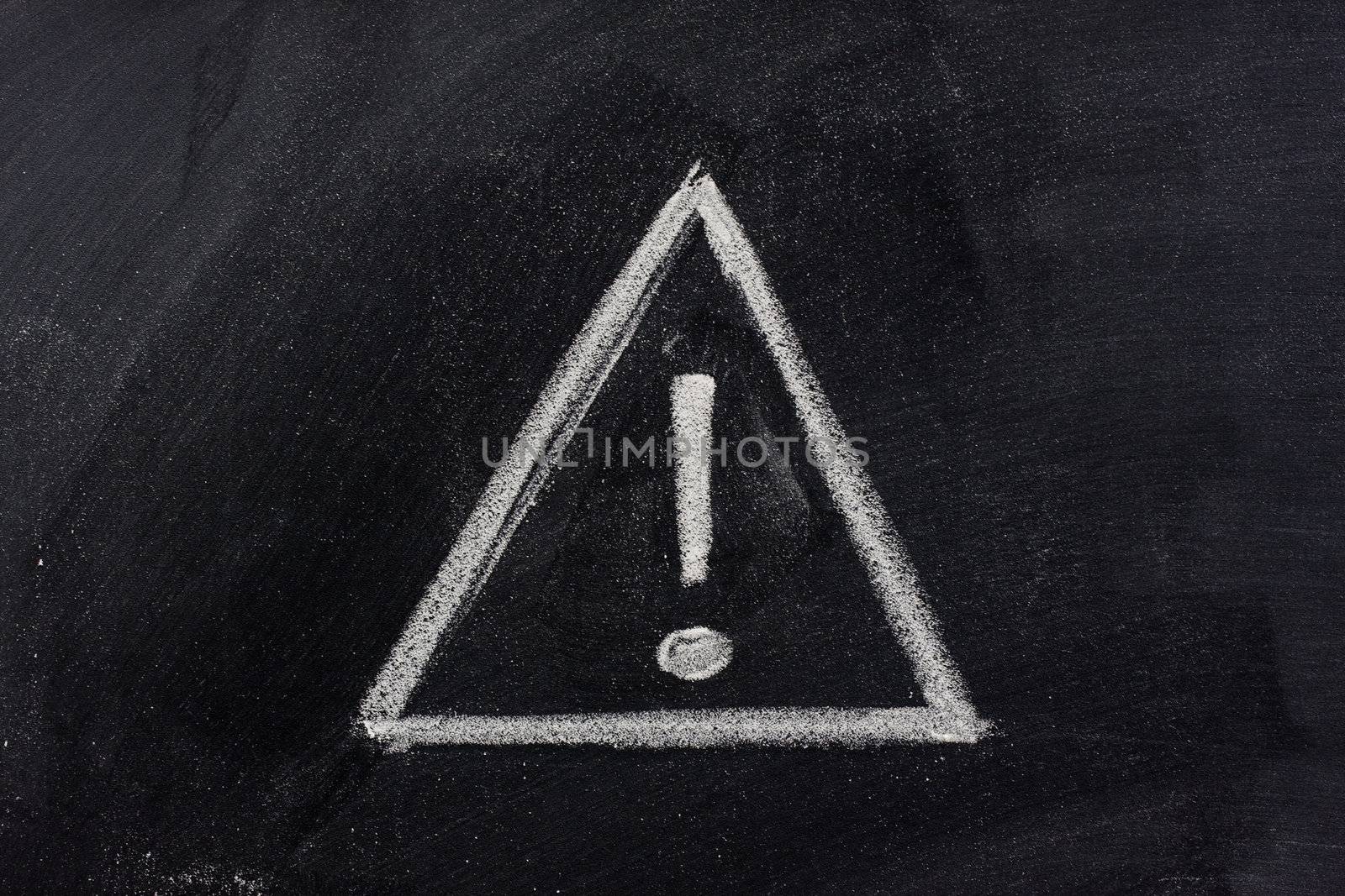 warning sign, exclamation mark inside a triangle, sketched with white chalk on blackboard