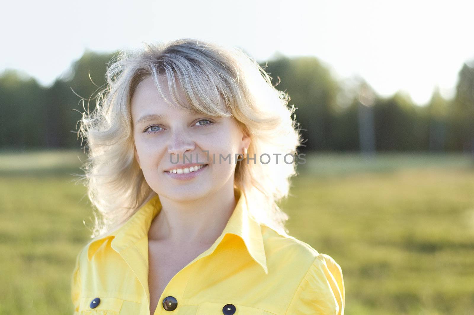 Portrait of smiling charming girl against summer green park