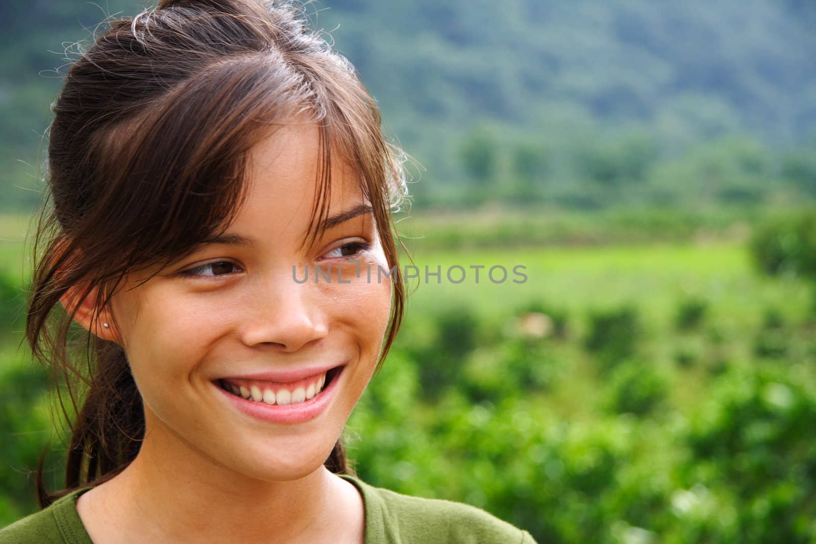 Young woman looking away outdoors with nature background.